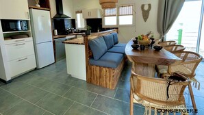 A modern kitchen with white cabinets, a built-in oven, and a dining area with a wooden table and wicker chairs.