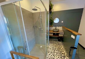 Ein modernes Badezimmer mit einer Duschkabine aus Glas, einem Holzkosmetikschrank und einem Mosaikboden.