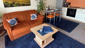 Un salon comprenant un canapé, une table basse, une table à manger et un coin cuisine.