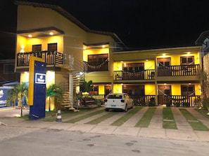 A multi-story hotel with balconies, a parking area, and a signboard. - Pousada Velosmar (Ipojuca)