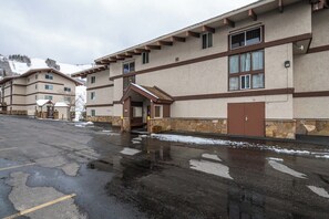 Un hôtel à plusieurs étages avec un parking et de la neige au sol.