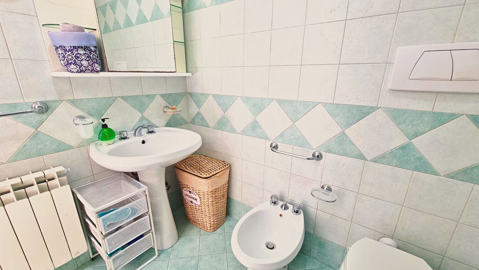 Een badkamer met een wastafel, bidet, toilet en een spiegel.