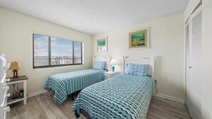 Un dormitorio con dos camas, una ventana, una lámpara y una puerta.