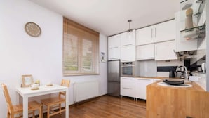 Una cocina moderna con armarios blancos, una mesa de comedor de madera y un horno empotrado.