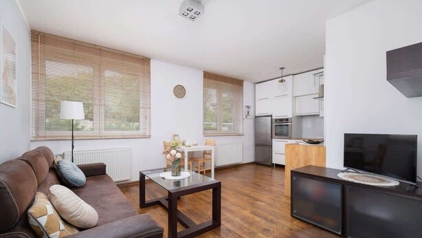 Una sala de estar moderna con un sofá de cuero marrón, una mesa de centro de vidrio y un mueble para televisión.