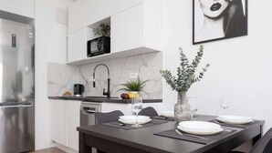A modern kitchen with white cabinets, a stainless steel refrigerator, and a marble backsplash. - Stylish Apartment in Praga | A Place to Work (Warszawa)