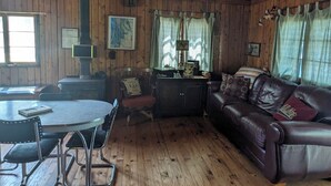 L’intérieur d’un chalet rustique, avec une table à manger en bois, un canapé en cuir et une cheminée.