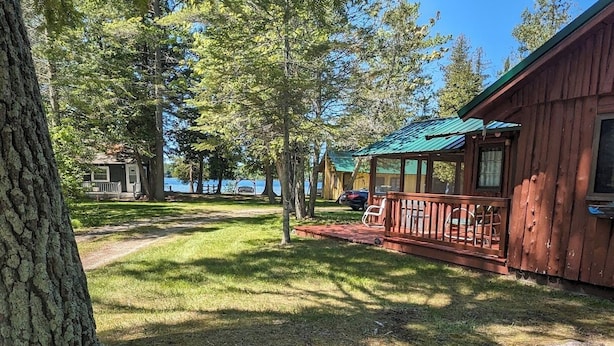 Une cabane avec une véranda, une terrasse et une vue sur un lac.