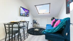 A compact living space with a dining table, chairs, a sofa, a TV, and a skylight. - Cosy 1-bedroom apartment in beautiful location in London with WiFi and Netflix (London)