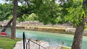 A stone staircase leading to a riverbank, surrounded by trees and a fence. - River City Resorts: RPS 104: River View Condo! Free Tubes Included! (New Braunfels)