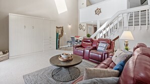 Un salon spacieux avec un plafond haut, un escalier et un coin repas.