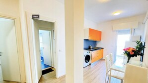 A modern apartment with a kitchen, dining area, and a visible laundry machine.