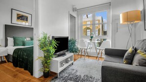 Ein modernes, gut beleuchtetes Zimmer mit einem Bett, einem Fernseher und einer Sitzecke.