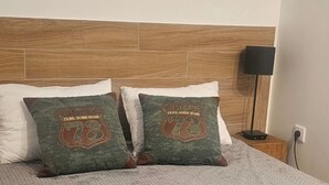 Sänky, jossa on kaksi koristeellista tyynyä. Tyynyissä on numero 73 ja teksti ”Vintage Prime Denim Brand”.
