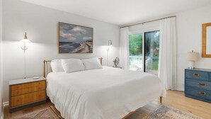 A bedroom with a bed, bedside lamps, a dresser, a mirror, and a painting of a beach scene. - Charming Home in Harbor Springs Close to Town and Skiing (Harbor Springs)
