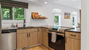 A modern kitchen with wooden cabinets, a built-in oven, and a dishwasher. - Charming Home in Harbor Springs Close to Town and Skiing (Harbor Springs)