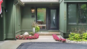 A green building with a black front door, a sign reading "RIVAGE RETREAT," and a mailbox. - Charming Home in Harbor Springs Close to Town and Skiing (Harbor Springs)