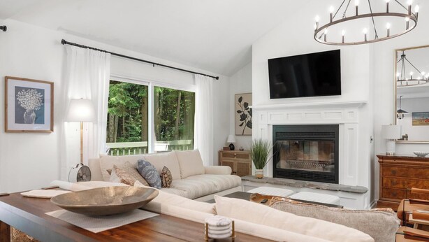 A living room with a fireplace, a large window, and a television. - Charming Home in Harbor Springs Close to Town and Skiing (Harbor Springs)