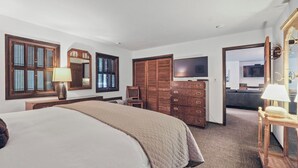 Ein Hotelzimmer mit einem großen Bett, einem Holzschrank, einem Fernseher und einem Spiegel.