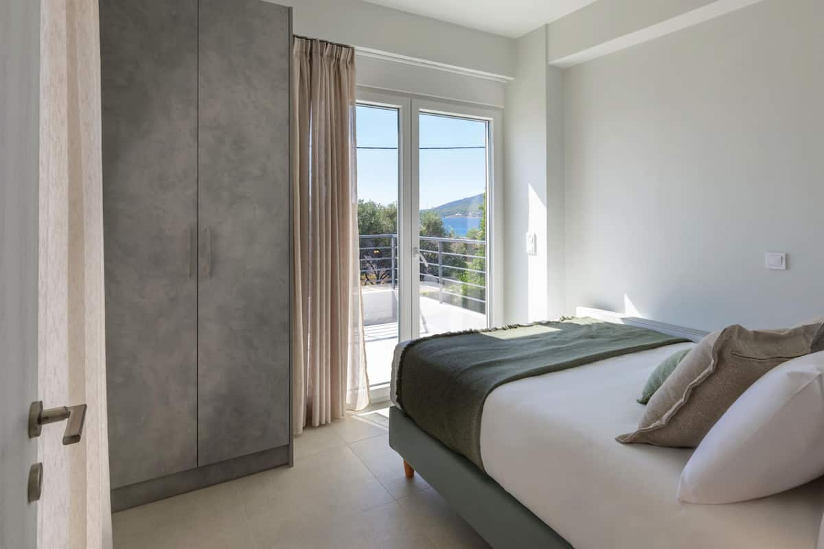 Un dormitorio con cama, armario y balcón con vistas al mar.