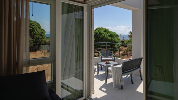 A balcony with a table, chairs, and a view of the sea and trees. - Komos Villas by Airstay (Spata-Artemida)