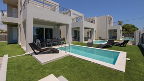 A modern building with a swimming pool, outdoor seating, and a well-maintained lawn. - Komos Villas by Airstay (Spata-Artemida)