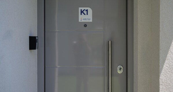 Μια γκρι πόρτα με την ε πιγραφή «K1» και μια λαβή.