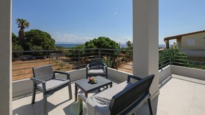 A balcony with a table and two chairs, overlooking a vineyard and the sea. - Komos Villas by Airstay (Spata-Artemida)
