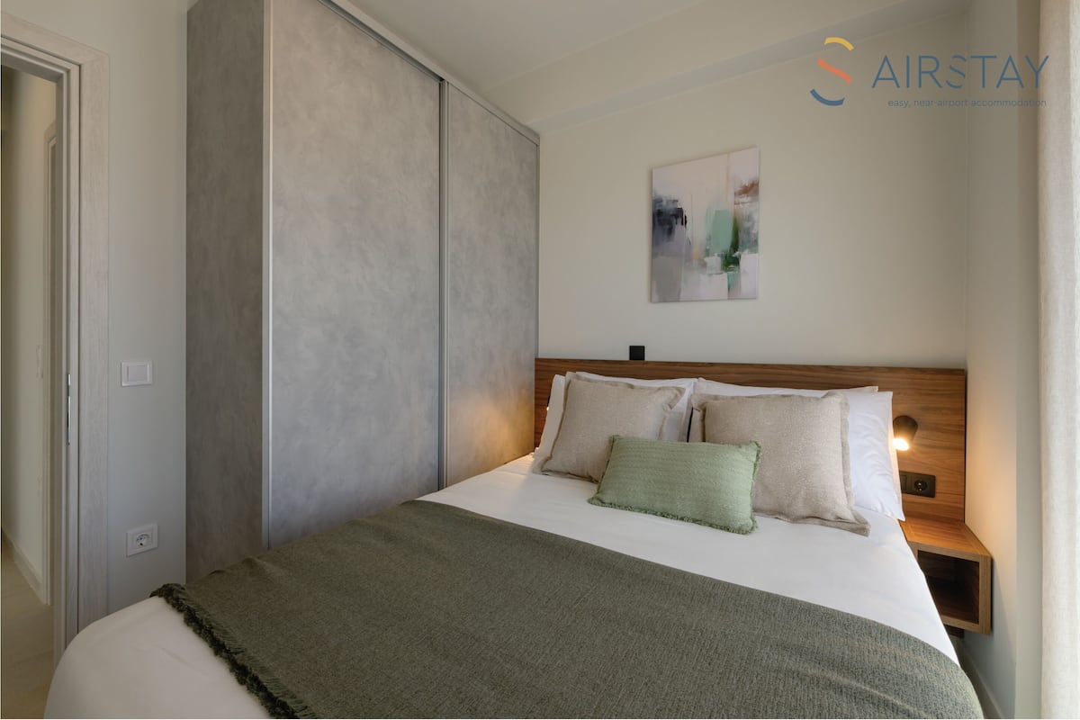 Una habitación de hotel moderna con una cama grande, un cabecero de madera y un cuadro en la pared.