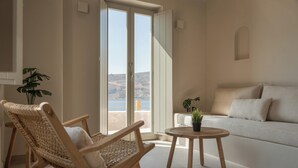 Een moderne woonkamer met een bank, twee rieten stoelen, een klein rond tafeltje en een potplant.