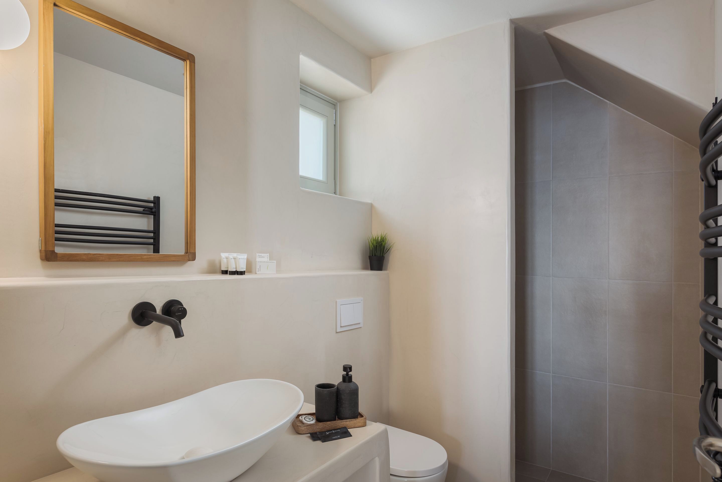 A modern bathroom with a freestanding bathtub, a large mirror, a towel rack, and a shower area.