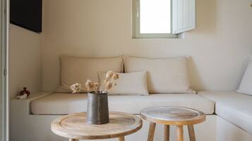 A minimalist living room with a sofa, two wooden side tables, and a vase with dried flowers.