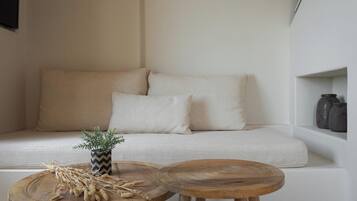 A minimalist living room with a sofa, two round wooden tables, and a small potted plant.