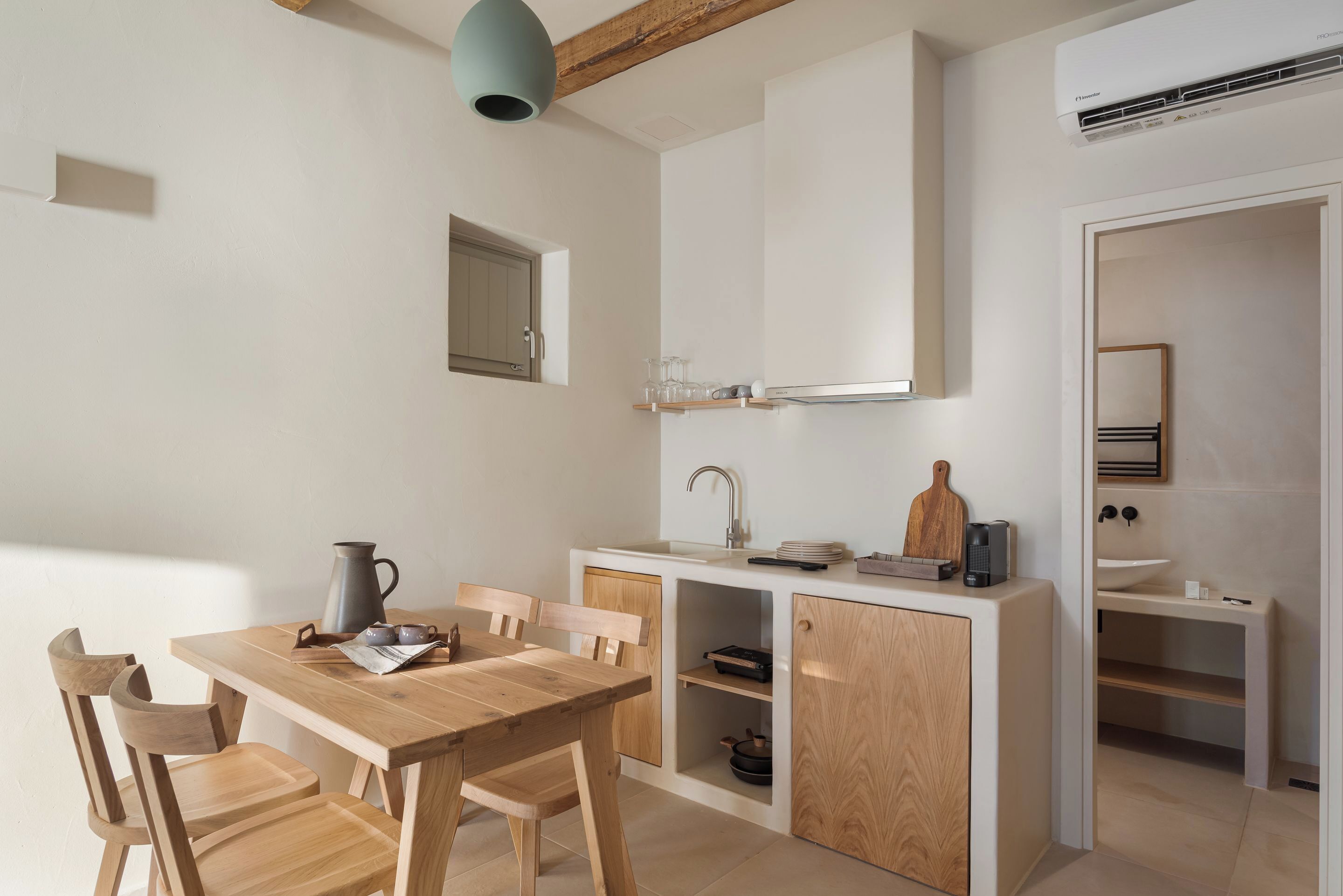 A compact kitchen with a wooden table and chairs, a built-in sink, and a small cabinet.