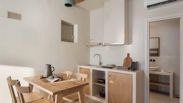 Een kleine keuken met een houten tafel en stoelen, een inbouwspoelbak en een kastje.