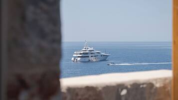 Un grand yacht sur des eaux calmes, vu depuis une structure en pierre.