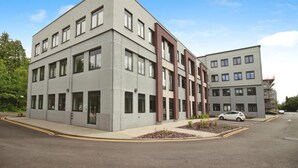 A modern multi-story building with a flat roof, rectangular windows, and a grey facade. - Modern Comfort: Seven Stays Broadoaks (Solihull)