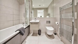 A modern bathroom with a bathtub, sink, toilet, and glass shower enclosure. - Modern Comfort: Seven Stays Broadoaks (Solihull)