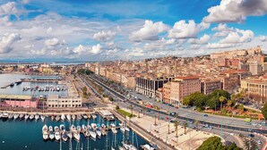 Paisagem costeira com marina, vias largas e edifícios históricos.