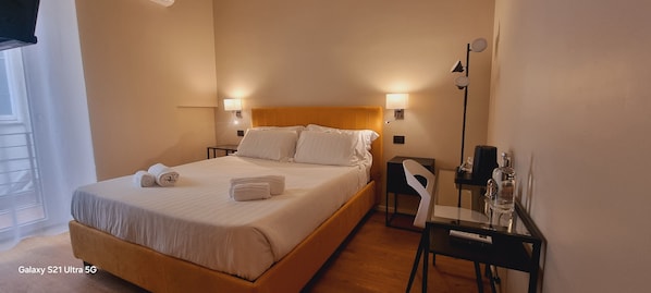 A hotel room with a bed, two bedside lamps, a chair, a small table, and a nightstand. - EVA LUXURY SUITE (Cagliari)