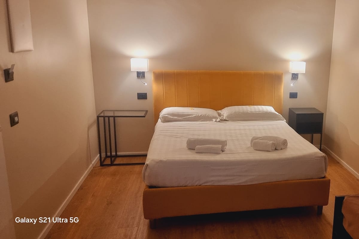 A hotel room with a bed, bedside tables, and a nightstand.