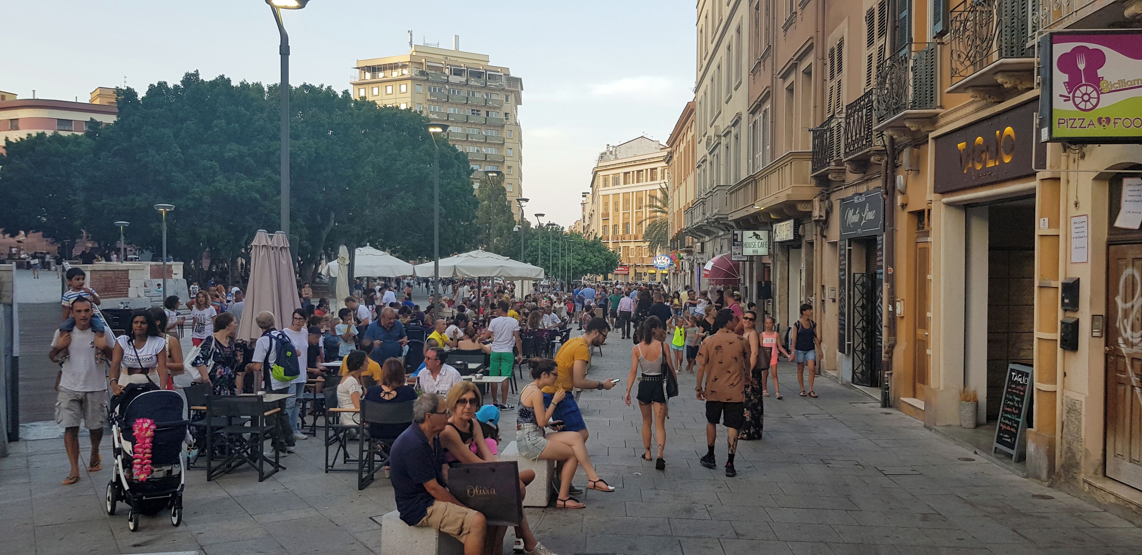 A crowded outdoor market with people walking and sitting.