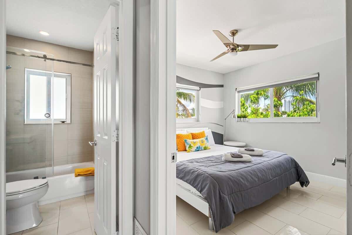 Een moderne slaapkamer met een bed, een raam en een plafondventilator.