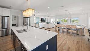 A modern kitchen with a large island, stainless steel appliances, and a chandelier. - Papa’s Beach House | 11BR/11.5BA Gulf Shores | Private Pool Coastal Escape (Gulf Shores)