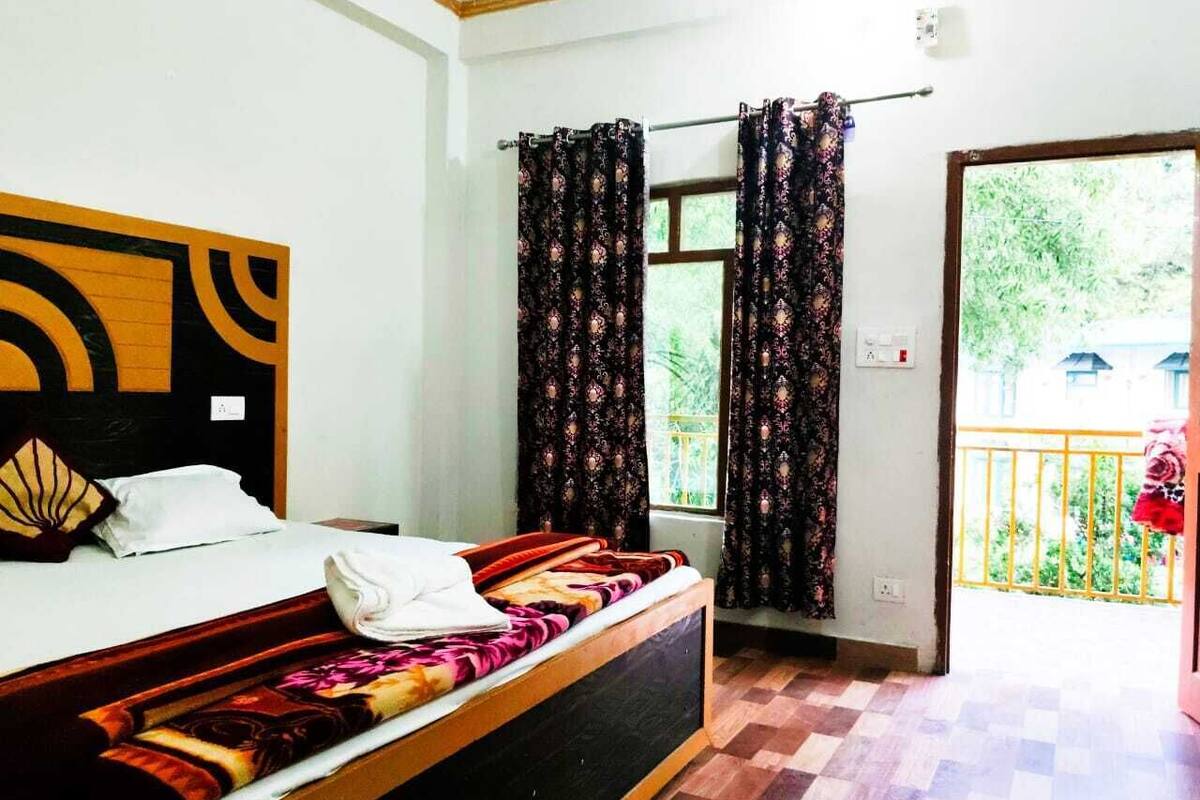 A hotel room with a bed, a window with curtains, a wooden headboard, and a balcony with a railing.
