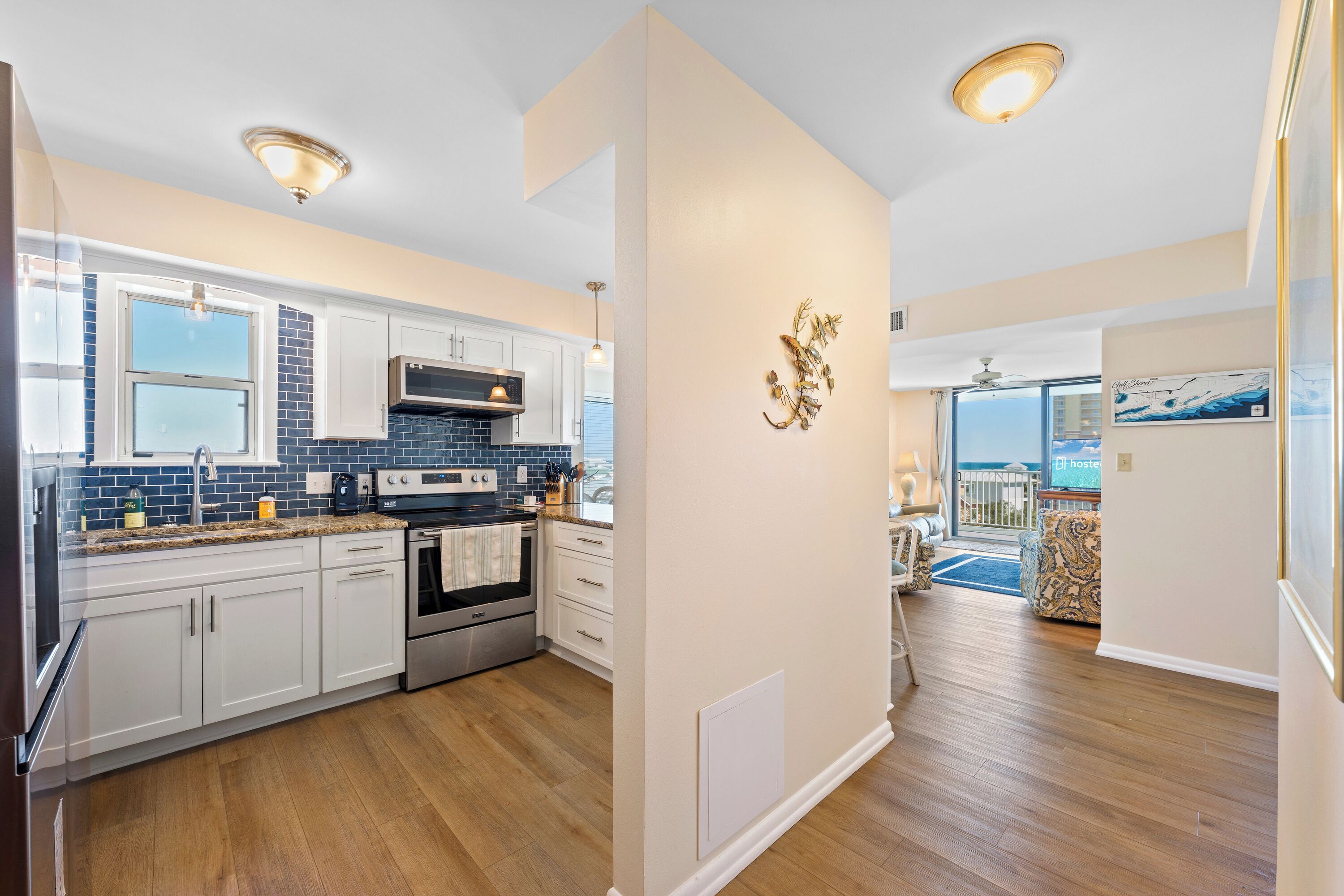 A modern kitchen with white cabinets, a black stove, and a blue tiled backsplash.