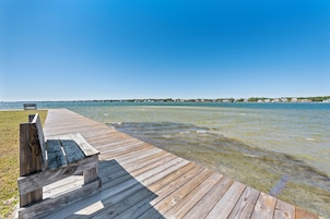 A wooden pier extending into a calm body of water with a clear sky above.