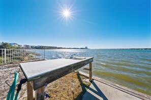A concrete bench by a waterfront with a metal railing and a hose.