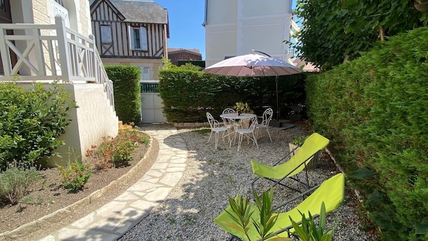 Un patio con un sendero de grava, mobiliario exterior y diversas plantas.