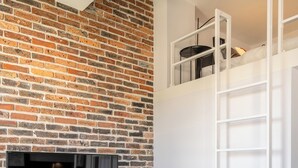 Une cuisine moderne avec un mur en briques, des meubles blancs et un coin repas comprenant une table et des chaises blanches.